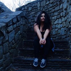 Full length portrait of young woman sitting on steps