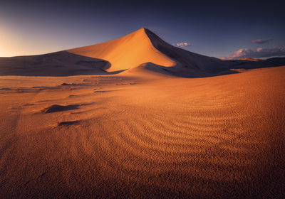 Scenic view of desert against sky during sunset