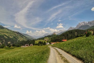 Road amidst green landscape against sky