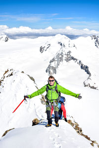 Full length portrait of male hiker on snowcapped mountain against sky