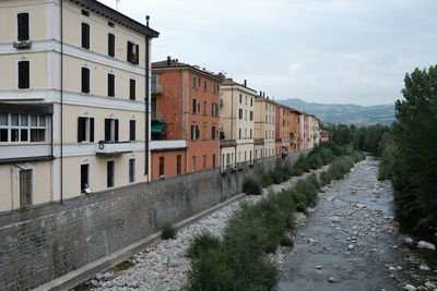 Buildings by road against sky in city