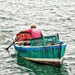 Rear view of men sitting on boat in sea