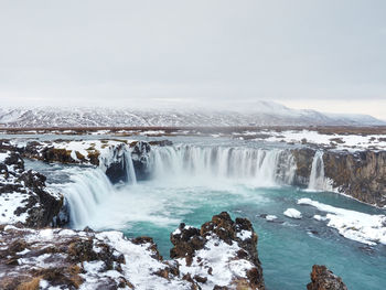 Scenic view of waterfall godafoss against sky during winter
