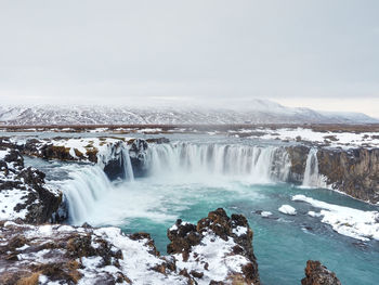 Scenic view of waterfall against sky during winter