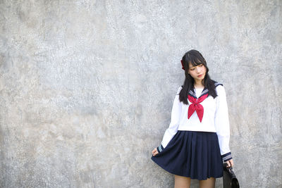 Young woman standing against wall