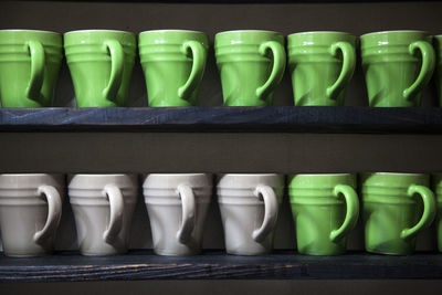 Green and white cups on wooden shelves