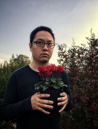 Portrait of young man holding flower