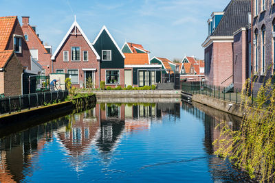 Canal amidst houses and buildings against sky