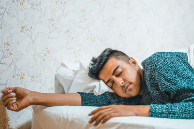 Young man sleeping on bed at home