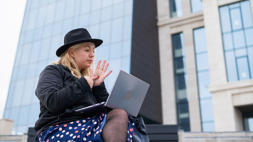 Low angle view of young woman using mobile phone in building