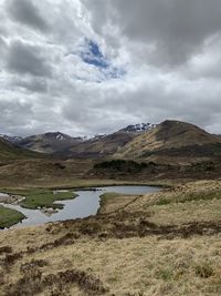 Scenic view of lake by mountain against sky