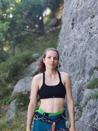 Portrait of smiling woman standing against rock