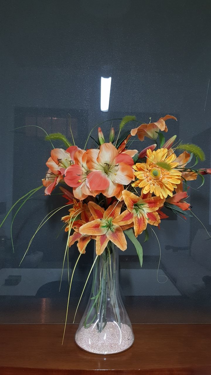 CLOSE-UP OF RED FLOWER VASE ON TABLE AGAINST WALL