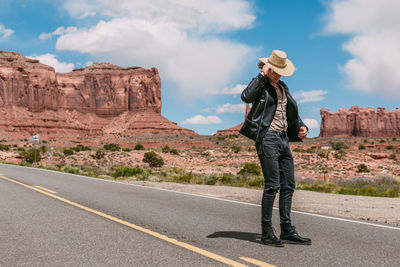 Side view of man standing on road against rock formation