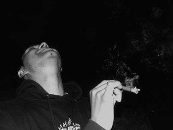 Man smoking cigarette against black background