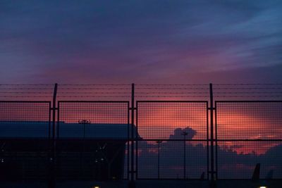 Silhouette fence against orange sky