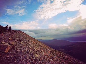 Male hikers hiking on mountain against sky