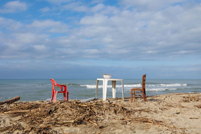 Two chairs and a plastic side table with a colander resting on top with wood remains.