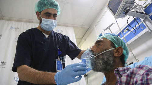 A nurse adjusts the oxygen machine for the patient. the breathing apparatus