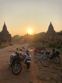 Bicycles against buildings in city at sunset