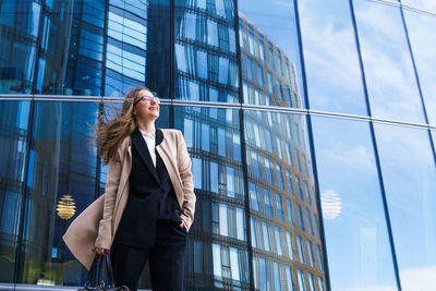 Portrait of a happy successful woman with glasses on the background of an office building