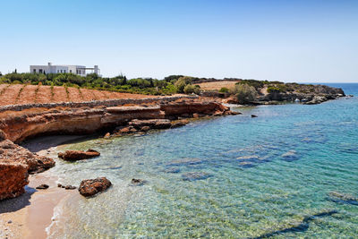 Rocks on beach against clear blue sky