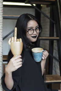 Close-up of woman holding wooden hand while drinking coffee