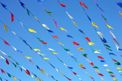 Low angle view of colorful buntings hanging against clear blue sky