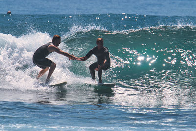 Full length of men splashing water at sea