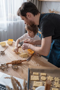 Cute preschool boy and his father baking cookies for international space day using video lesson