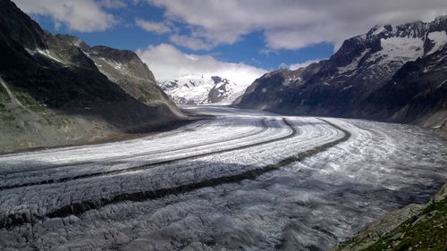 Snow covered road amidst mountains against sky