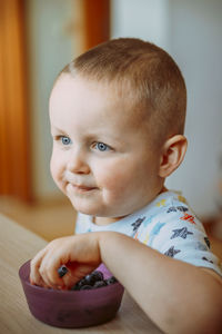 Portrait of cute baby boy eating blueberries at home