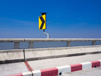 Low angle view of yellow sign against blue sky