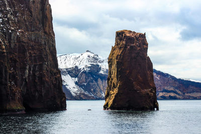 Scenic view of sea by mountain against sky