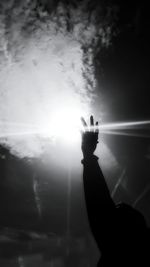 Cropped image of man raising hand against shining sun