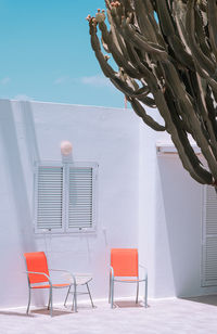 Empty chairs and chair against sky