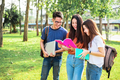 Friends studying while standing at park