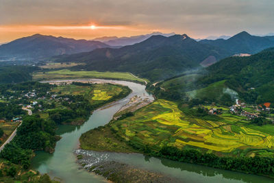 Scenic view of river amidst mountains against sky during sunset