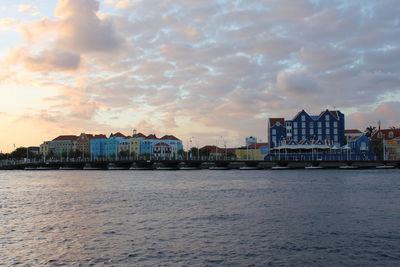 River in city against sky during sunset