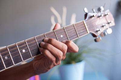 Cropped hand playing guitar at home