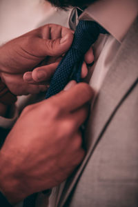 Midsection of man adjusting necktie