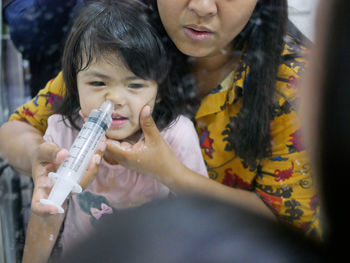 Asian mom rinsing her baby's stuffy nose using a syringe of saline water