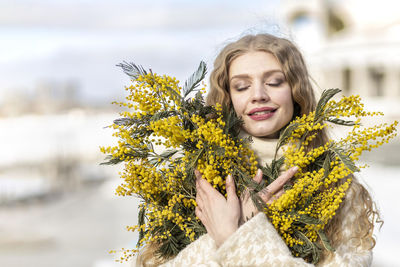 A woman  with a bouquet of yellow acacia flowers.the concept of the- march 8, easter, women's day.