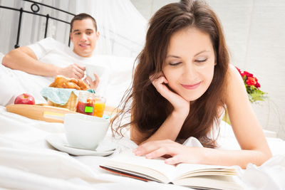 Smiling young woman sitting on bed at home