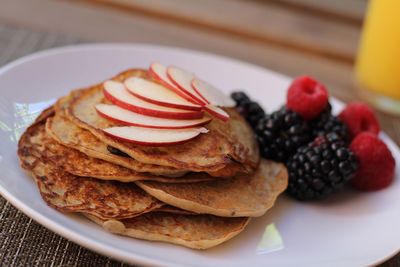 Close-up of pancakes in plate with apple slices and berry fruits