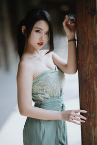 Portrait of young woman standing against wall