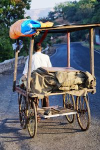 Rear view of man seen through push cart on road