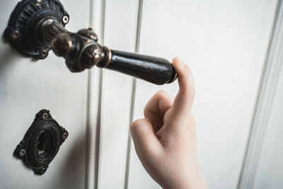 Close-up of hand holding metal against wall