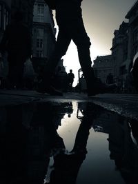 Low section of silhouette man with reflection in puddle