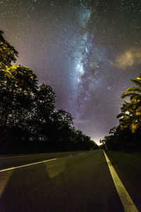Road amidst trees against sky at night